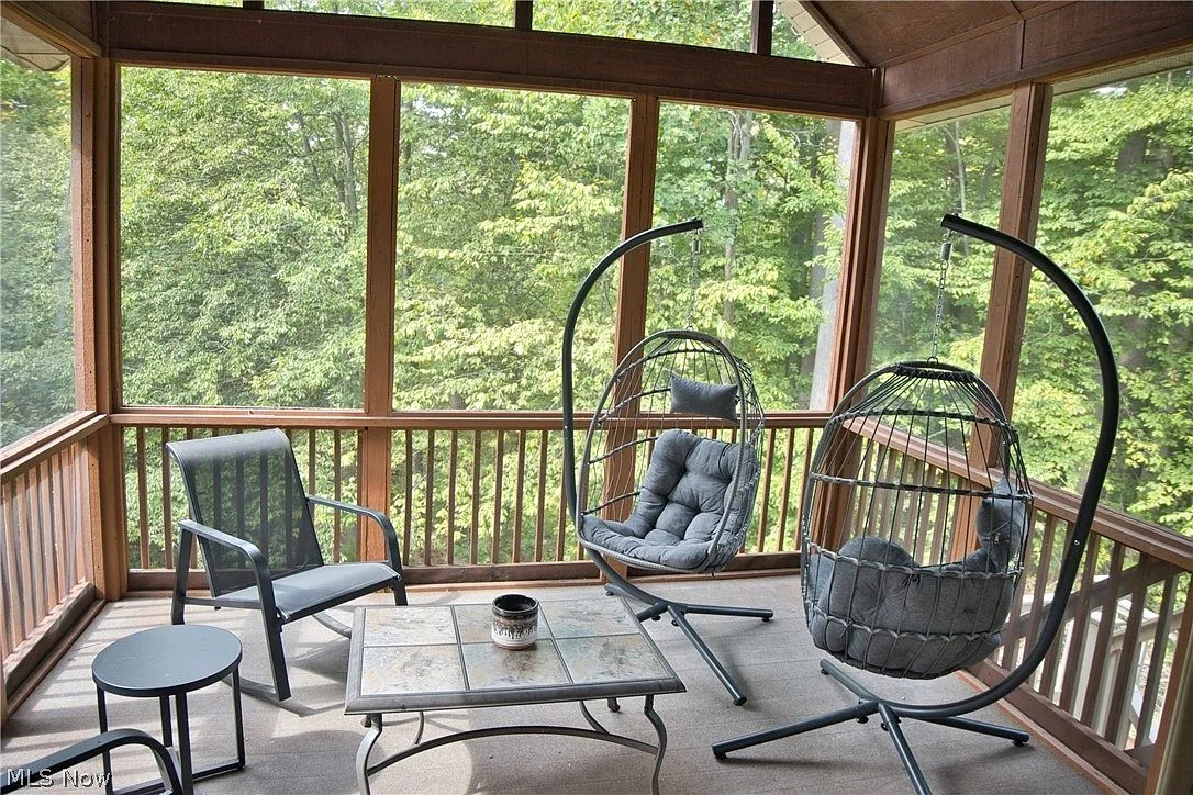 Three-season sunroom with floor-to-ceiling screens and forest views