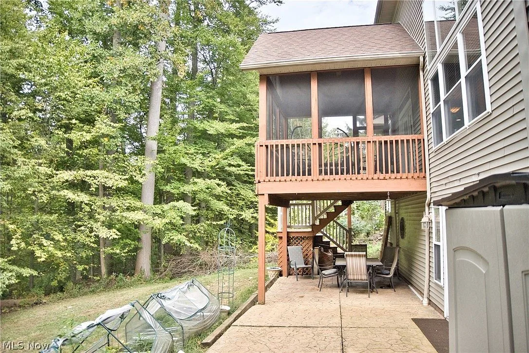 Backyard with deck, patio, and mature trees behind the home
