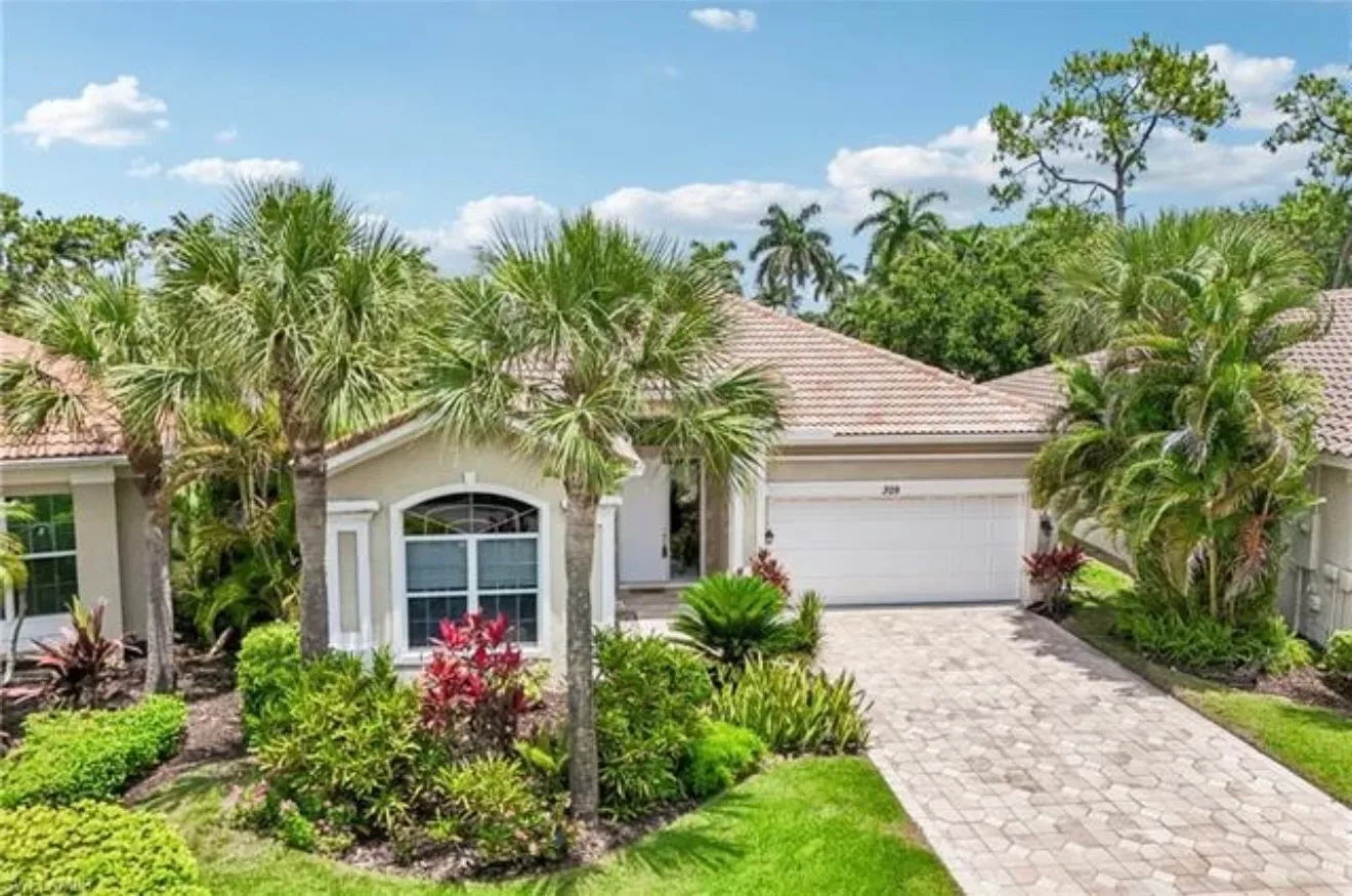 Front exterior of 309 Harvard Ln, Naples, showing the beige stucco facade, brown tiled roof, and landscaped palm front yard