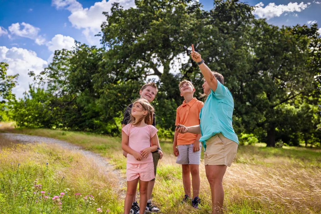 A family standing in an open North Texas meadow with new homes in the distance