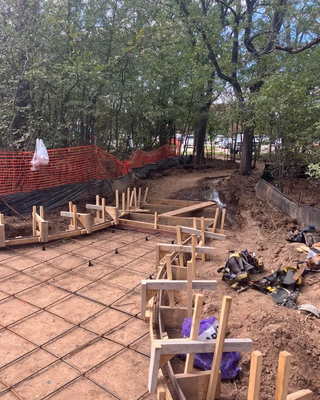Foundation and rebar grid at the Argyle Nature Trail construction site on Cook Street in Argyle, framed by trees