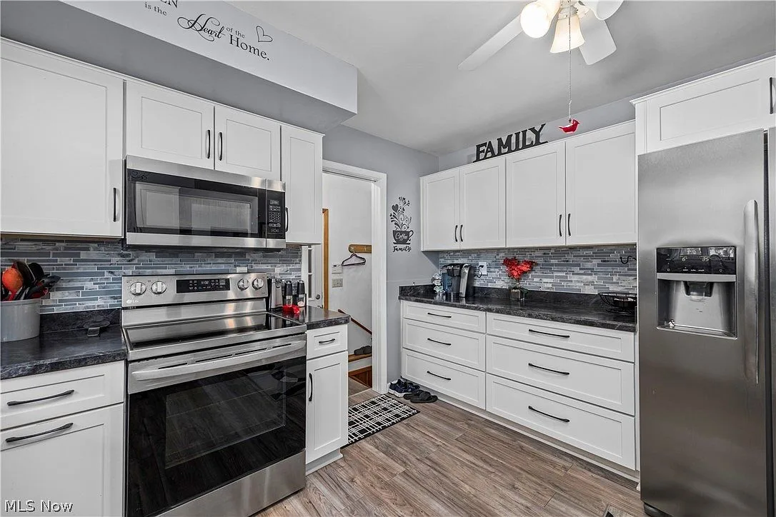 Updated kitchen with white shaker cabinets, dark counters, and stainless steel appliances