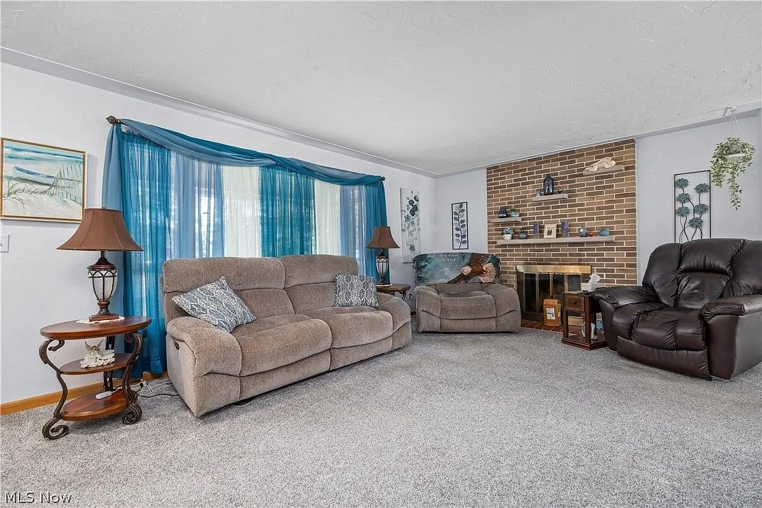 Living room with a brick fireplace wall and bright indoor lighting