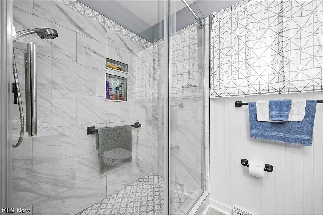 Modern tiled shower with marble-look walls and a glass enclosure