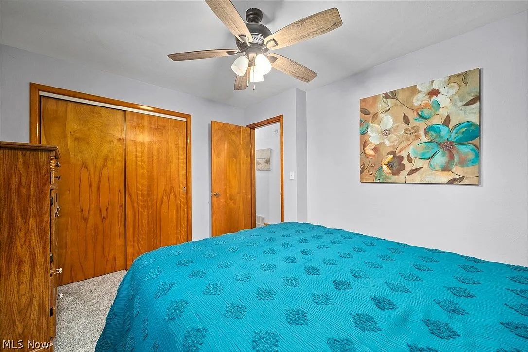Bedroom with neutral walls, carpeting, and wood-toned closet trim