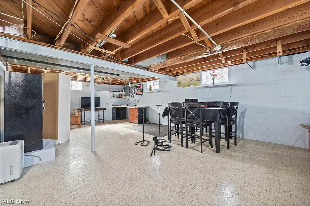 Basement recreation room with open-beam ceiling and painted cinder block walls