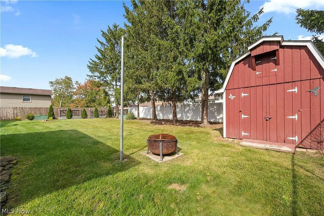 Large grassy backyard with a red barn-style storage shed and fenced perimeter