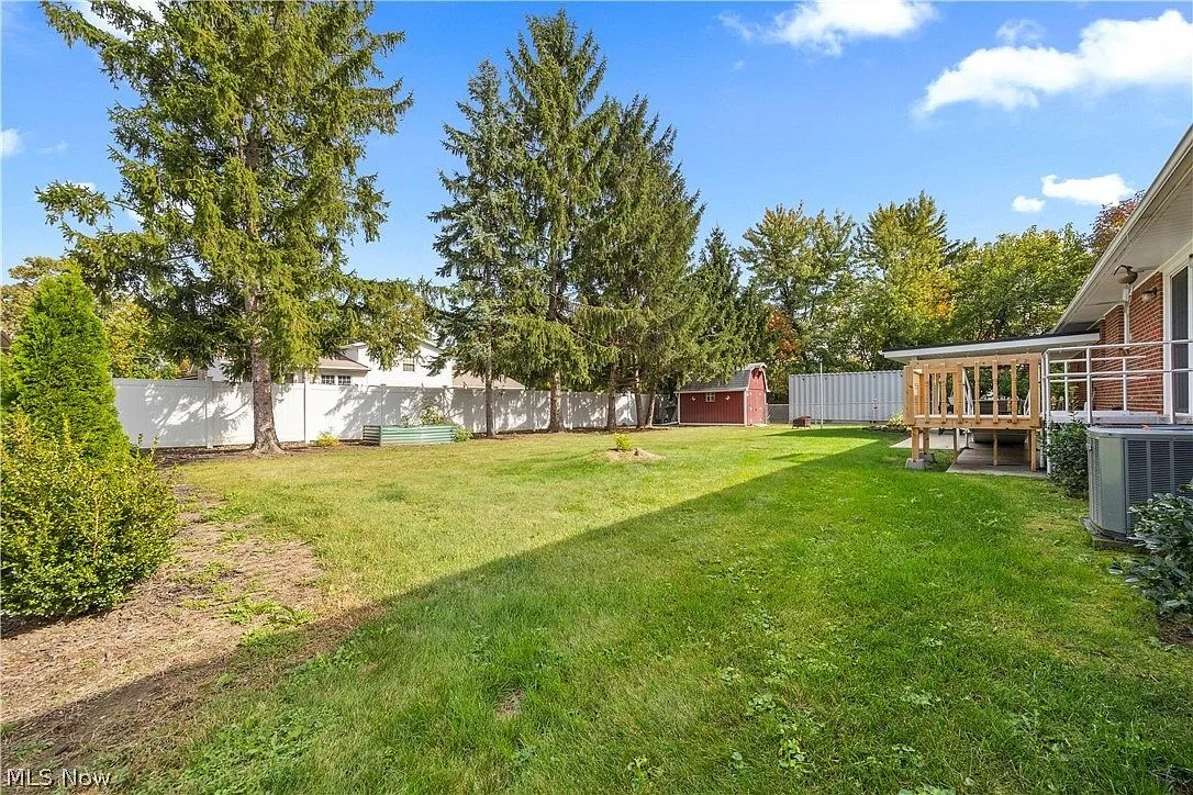 Spacious fenced backyard with a raised garden bed and a red garden shed