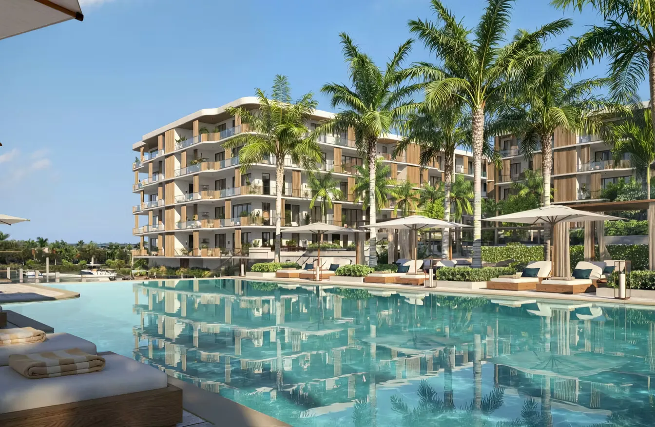 Piscina estilo resort de The Halcyon Residences and Marina con tumbonas, sombrillas y palmeras frente a las torres de altura media