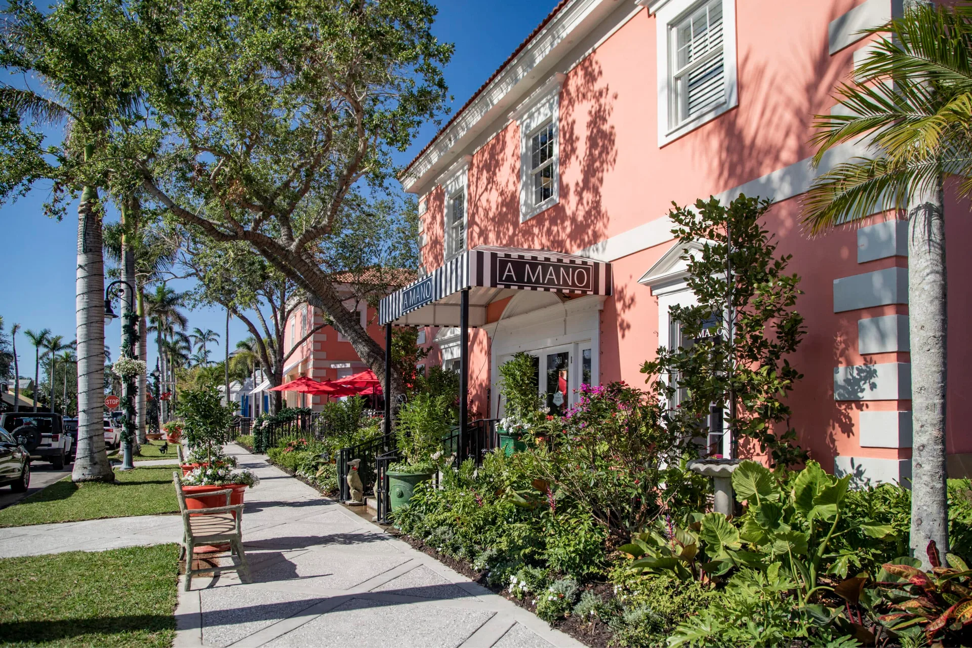 La fachada rosa de la tienda A MANO en la calle de Napoles, Florida, un edificio estilo mediterraneo con toldo de tela a rayas