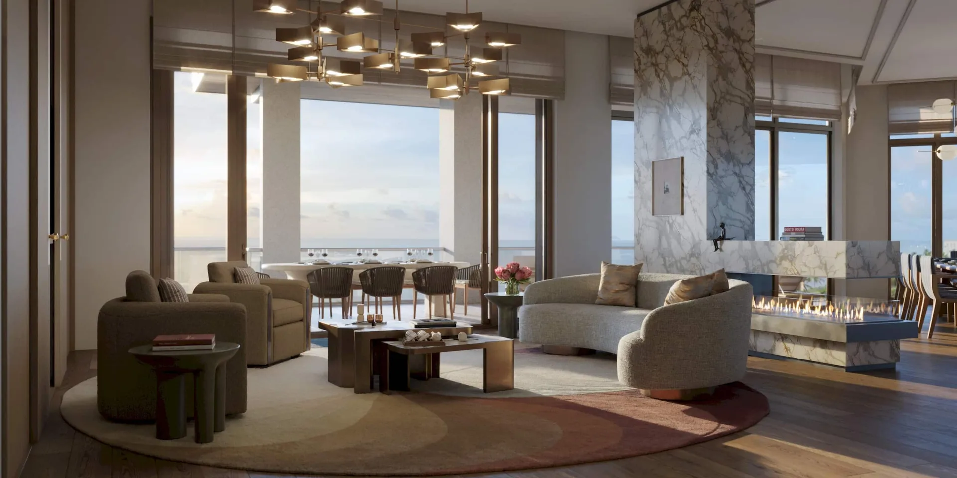 Chimenea de la sala de estar del penthouse en Rosewood Residences Naples con muro de piedra y ventanales de piso a techo