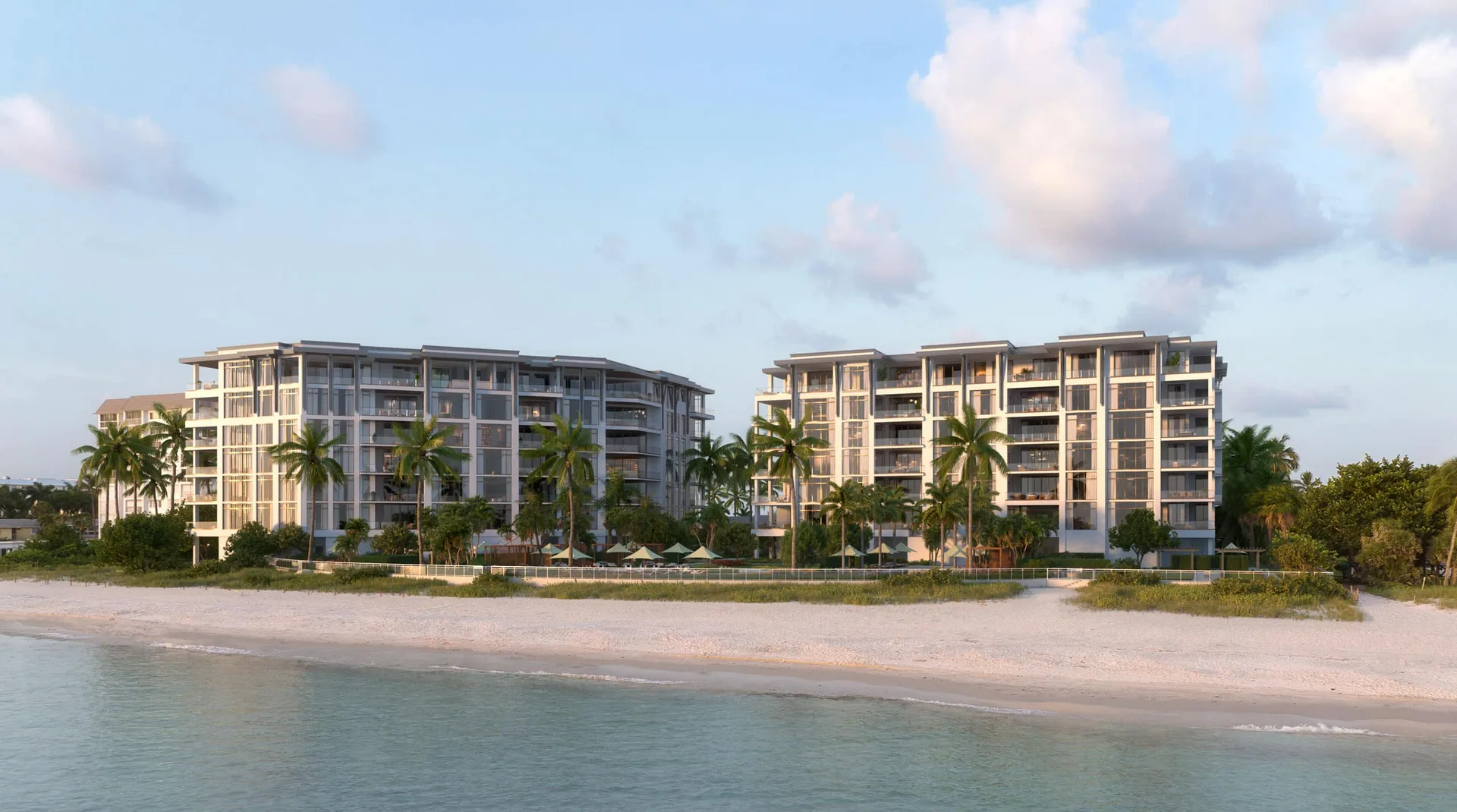 Vista aerea de Rosewood Residences Naples, un complejo de condominios frente a la playa con balcones de cristal, palmeras, una piscina privada y la playa del Golfo en primer plano