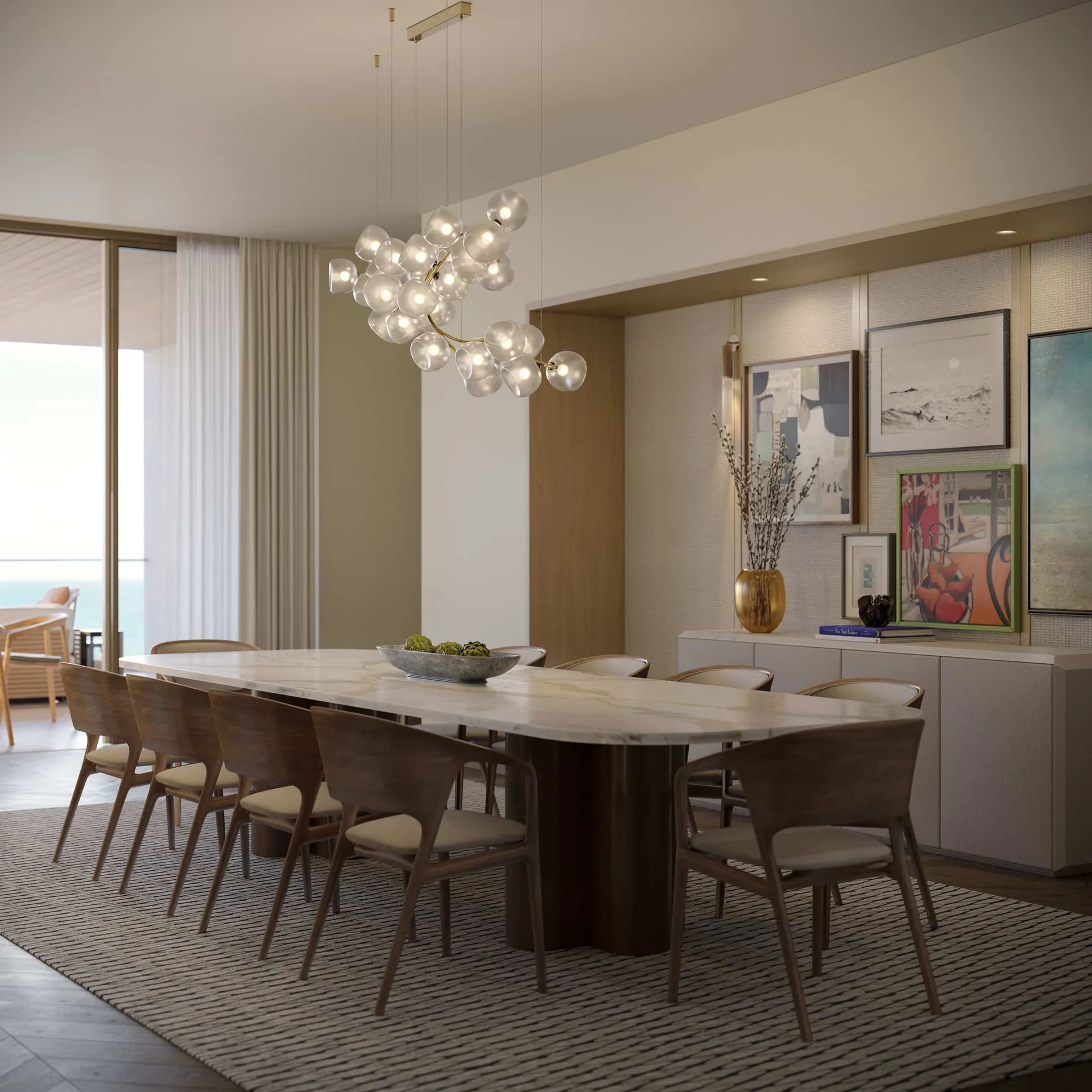 Comedor en Rosewood Residences Naples con mesa de piedra, base esculpida y sillas de madera calida