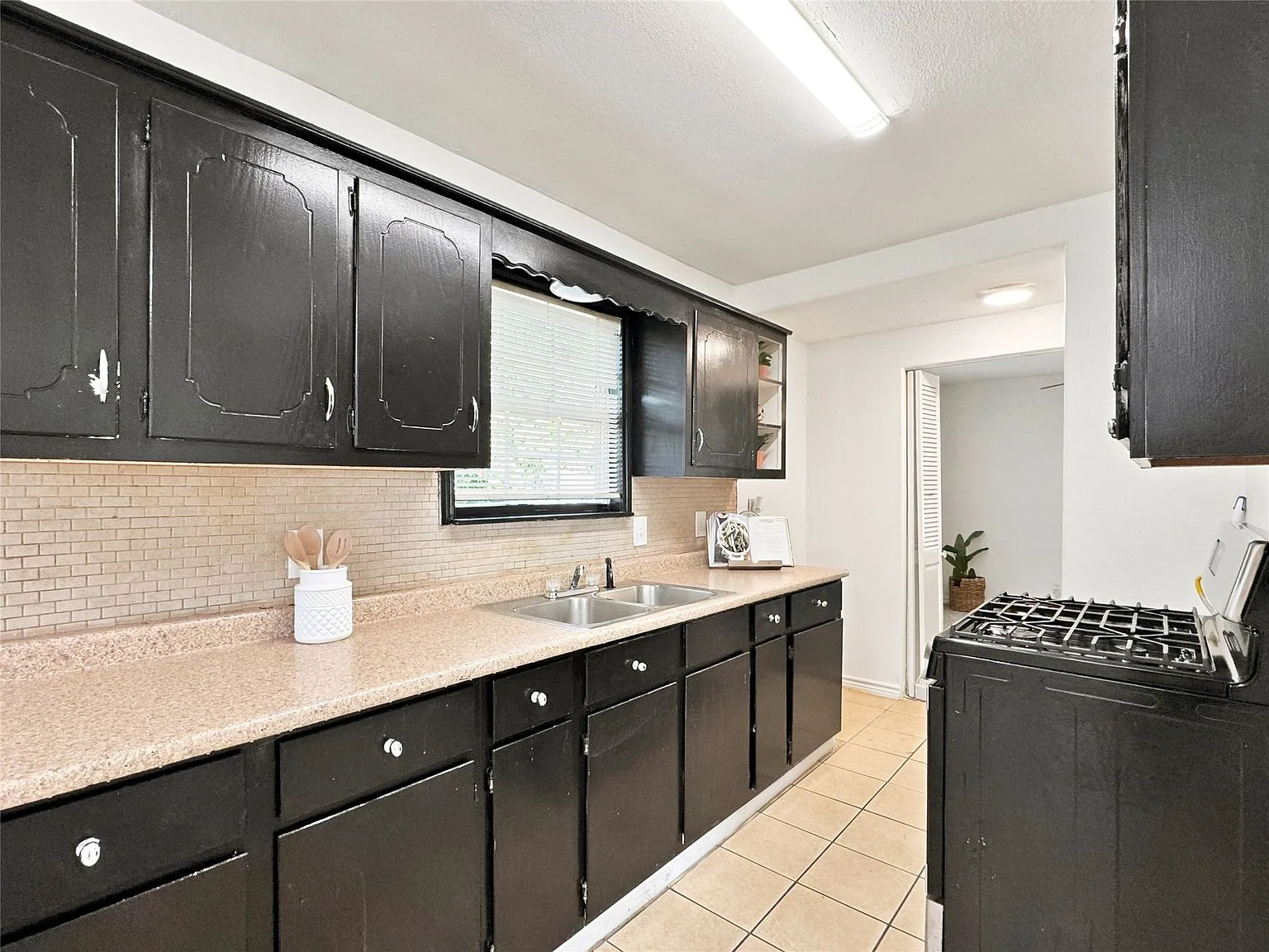 Galley kitchen with black cabinets and laminate counters