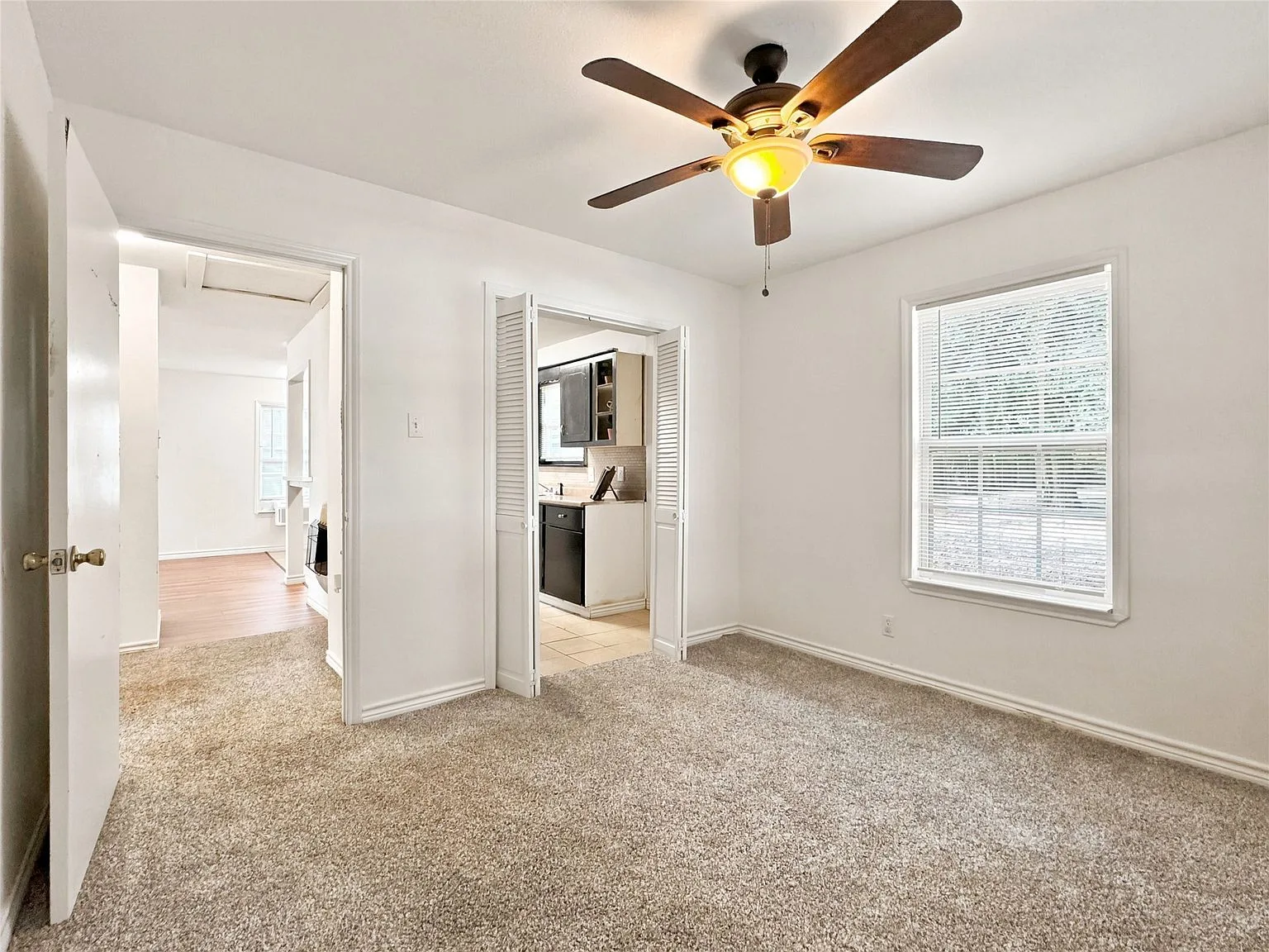 Primary bedroom with beige carpet and neutral white walls