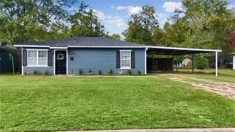 The full street view of 1145 16th St NW: both ends of the ranch home, the attached carport, the complete roofline with sky above, and the front lawn
