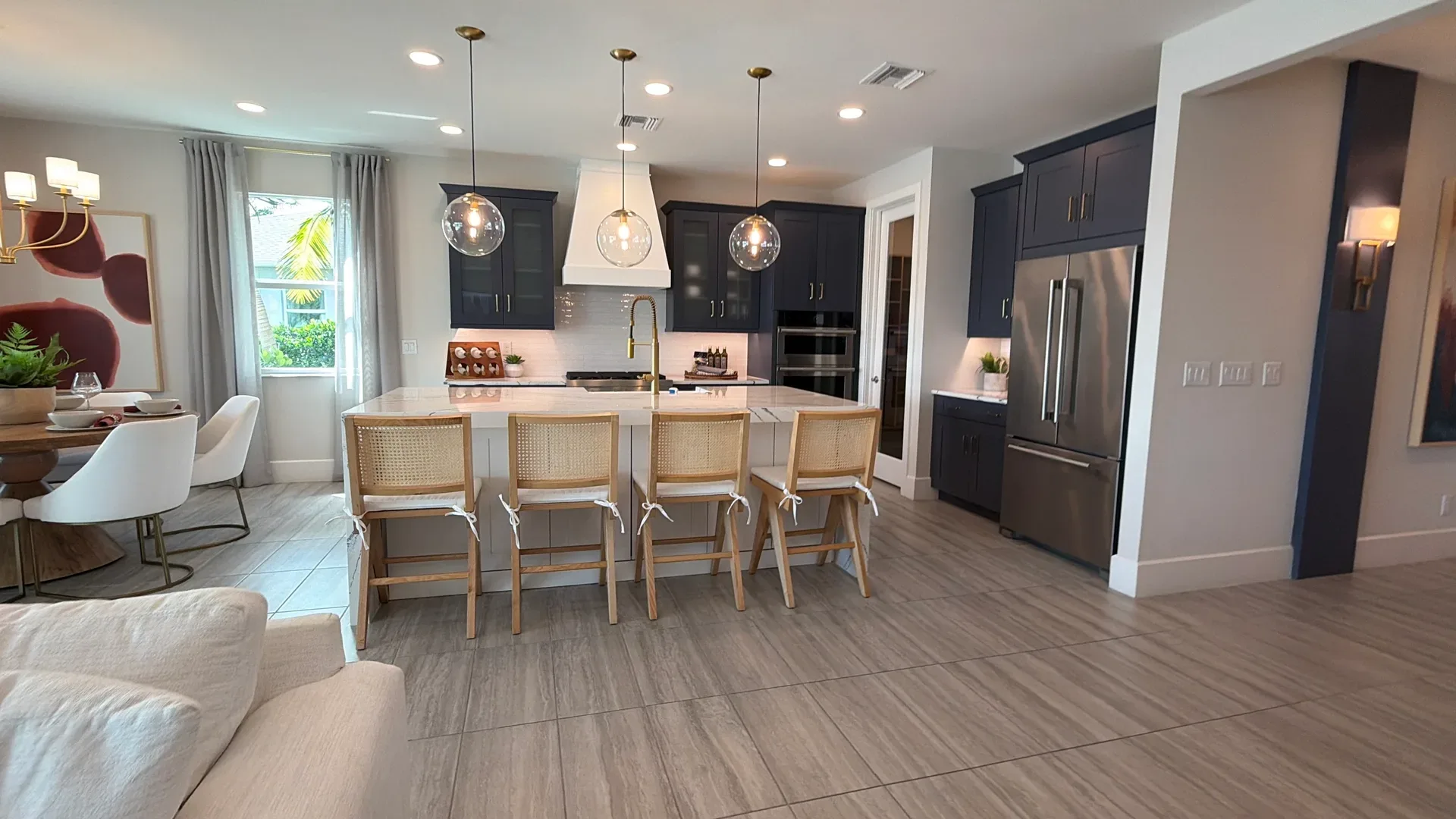 Open-concept kitchen with navy cabinetry, white countertops, and a dining area in a Regency at Babcock Ranch home