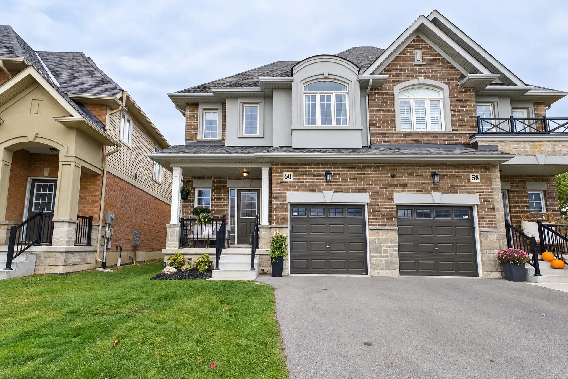 Front facade of 60 Starling Drive, a two-storey brick and stone townhome with grey shingles and an attached garage