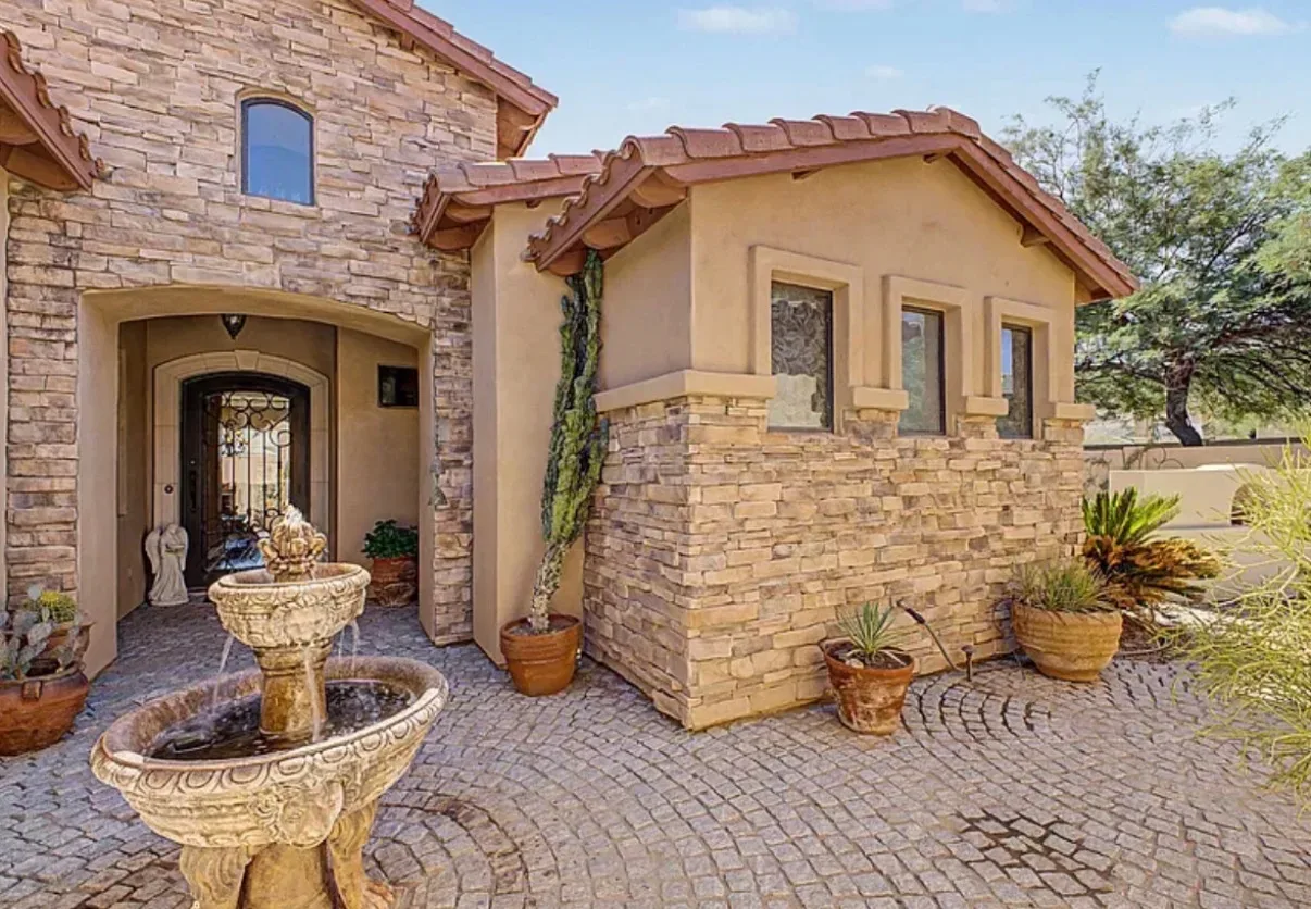 Stone courtyard entrance of the villa with a water fountain and potted plants