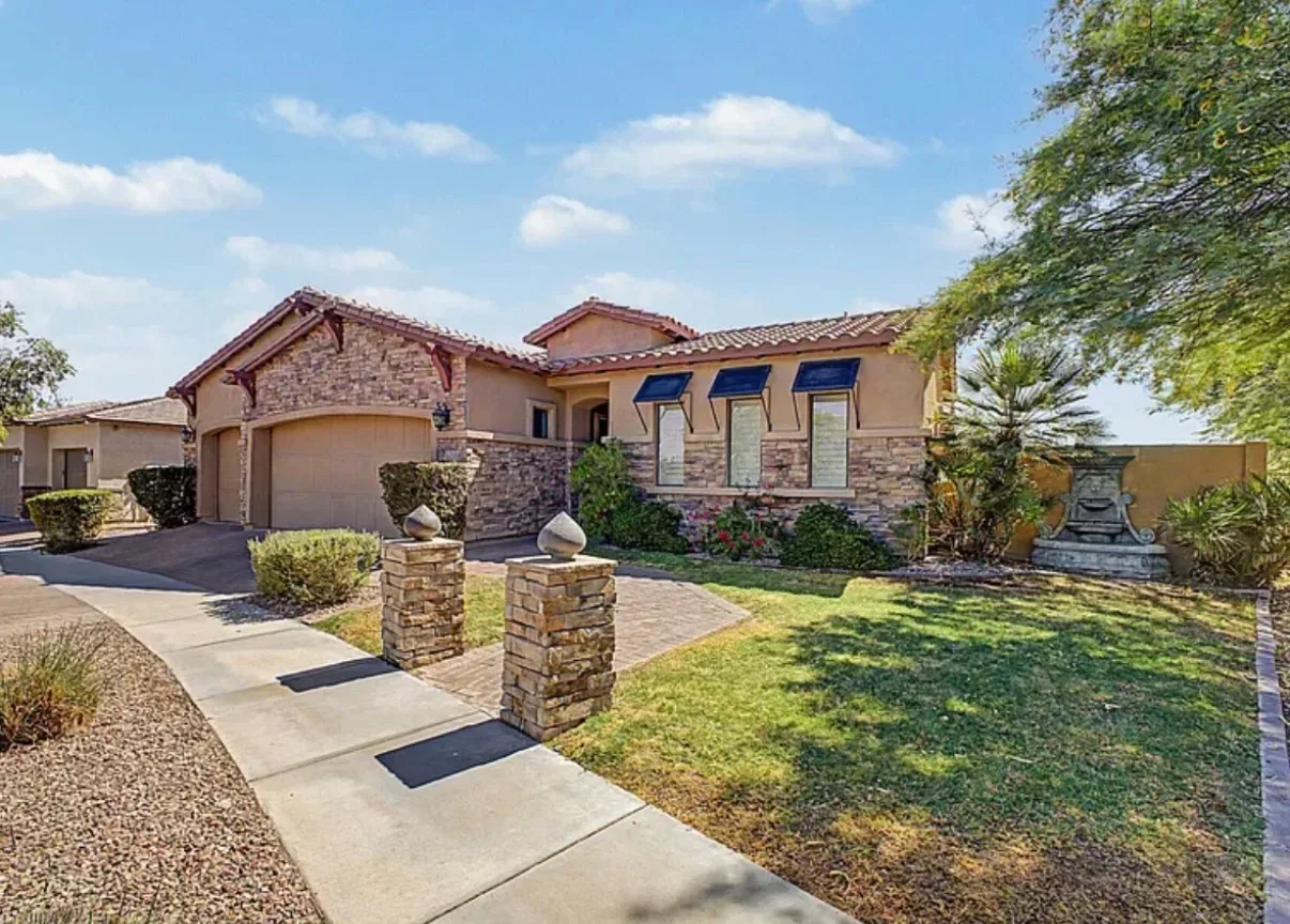 Front facade of the Tuscan villa at 3238 E Mountain Village Cir with stacked stone, clay tile roof, and a front-yard fountain