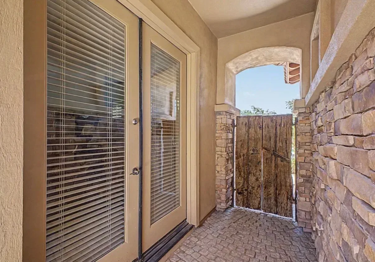 Courtyard entryway with a rustic wooden gate and stone-paver flooring