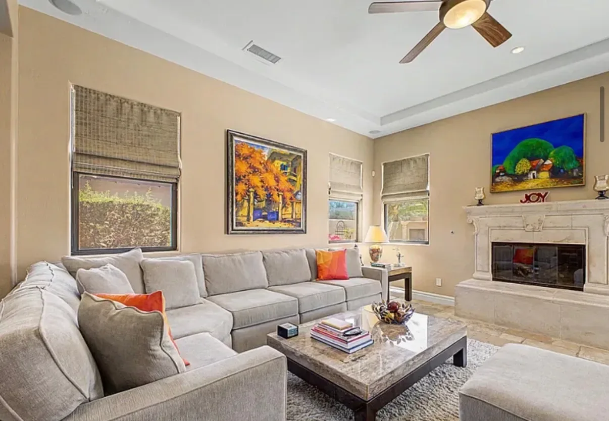 Living room with a stone fireplace, tray ceiling, and tall windows
