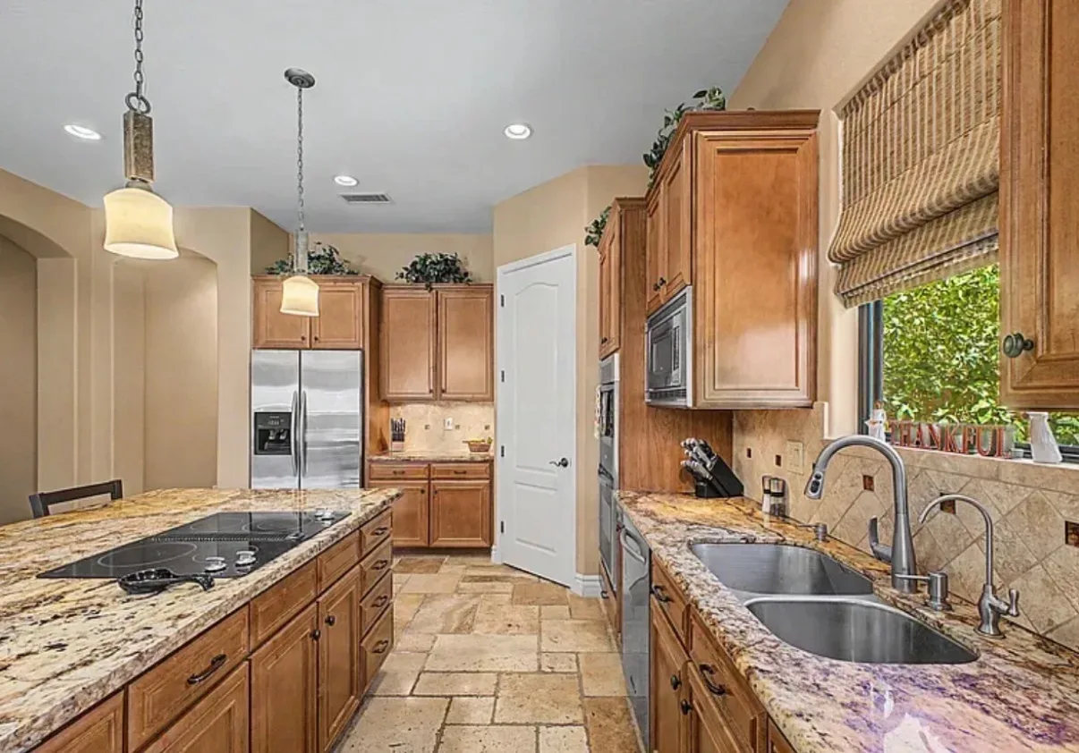 Kitchen detail with warm wood cabinetry, granite, and pendant lights