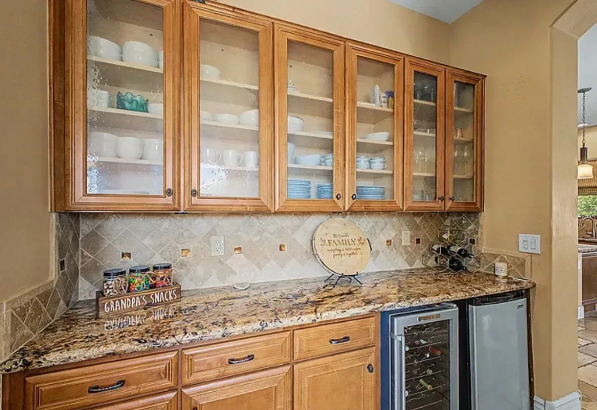 Butler pantry with glass-front cabinetry, a wine fridge, and stone backsplash