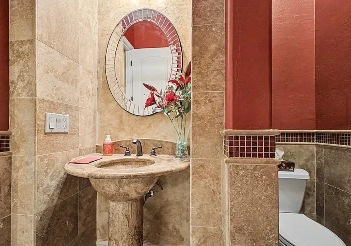 Powder room with travertine walls and a pedestal sink
