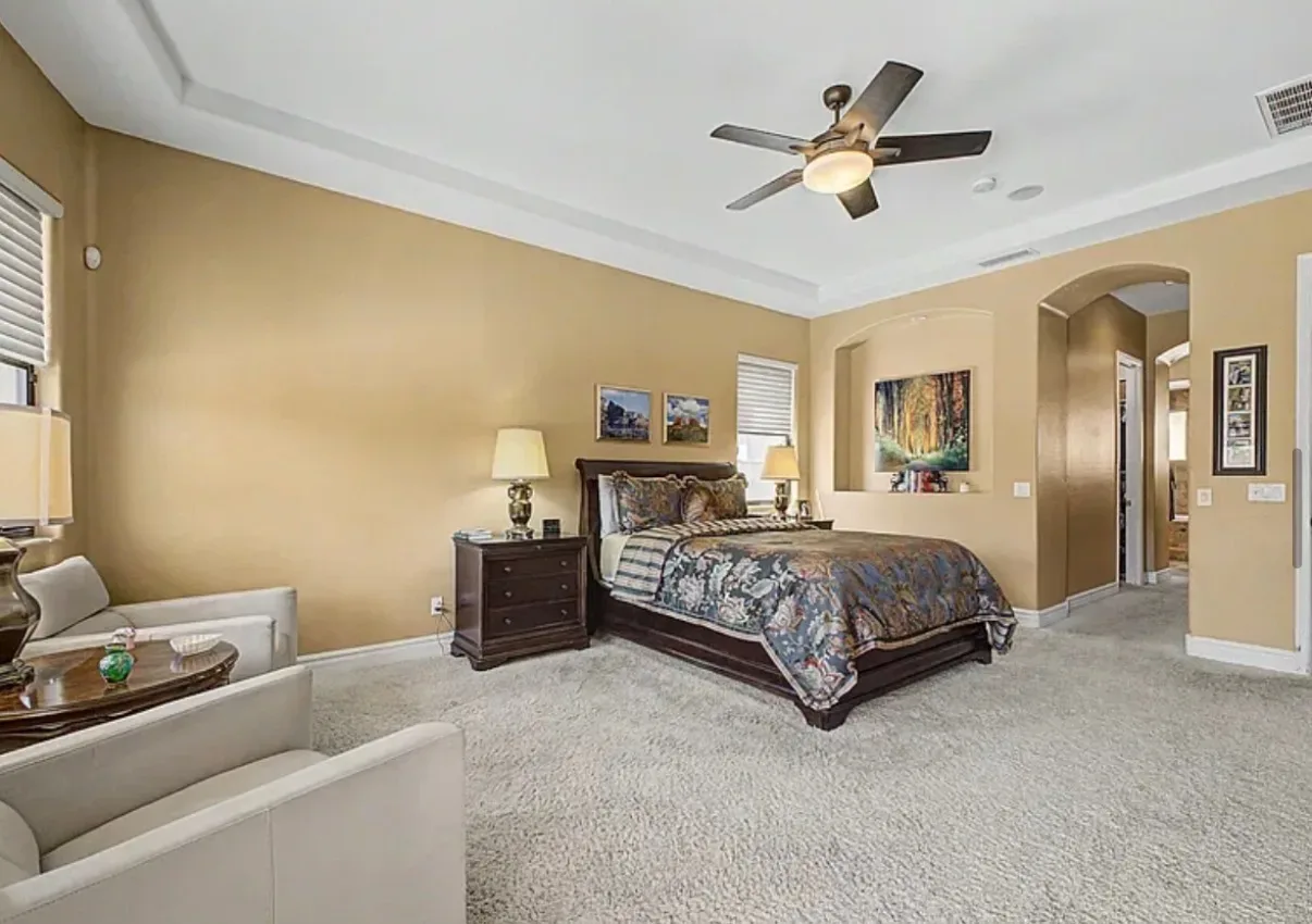 Primary bedroom suite with a tray ceiling and accent chairs