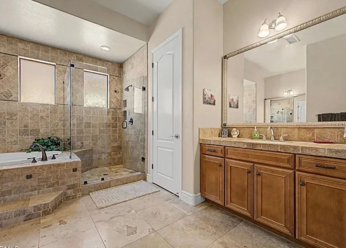 Primary bathroom with travertine tile, a tub, and a walk-in shower