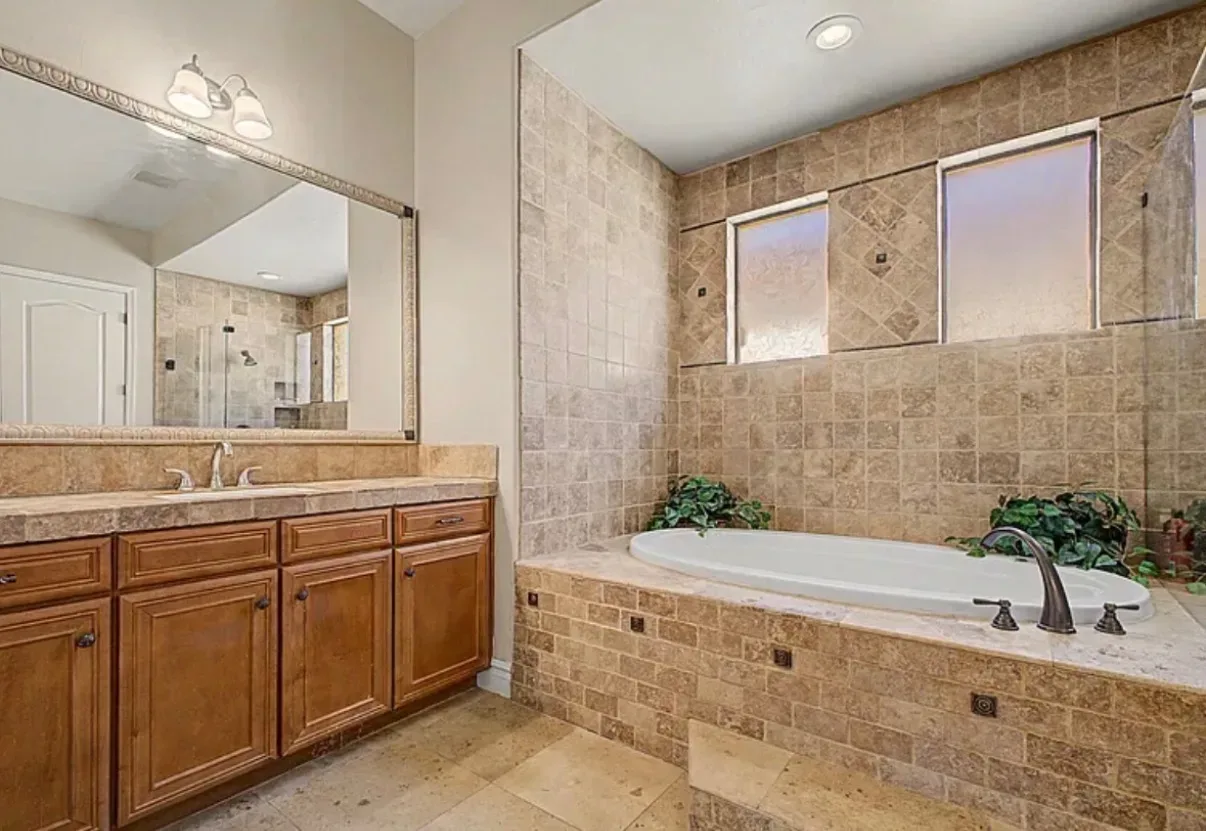 Primary bathroom vanity with a soaking tub in travertine tile