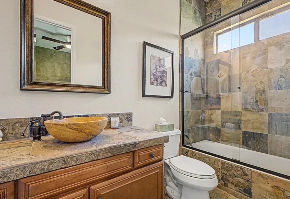 Bathroom vanity with a natural stone vessel sink and wood cabinetry