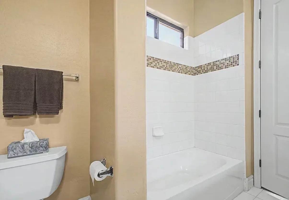 Bathroom tub and shower with white tile and a mosaic accent