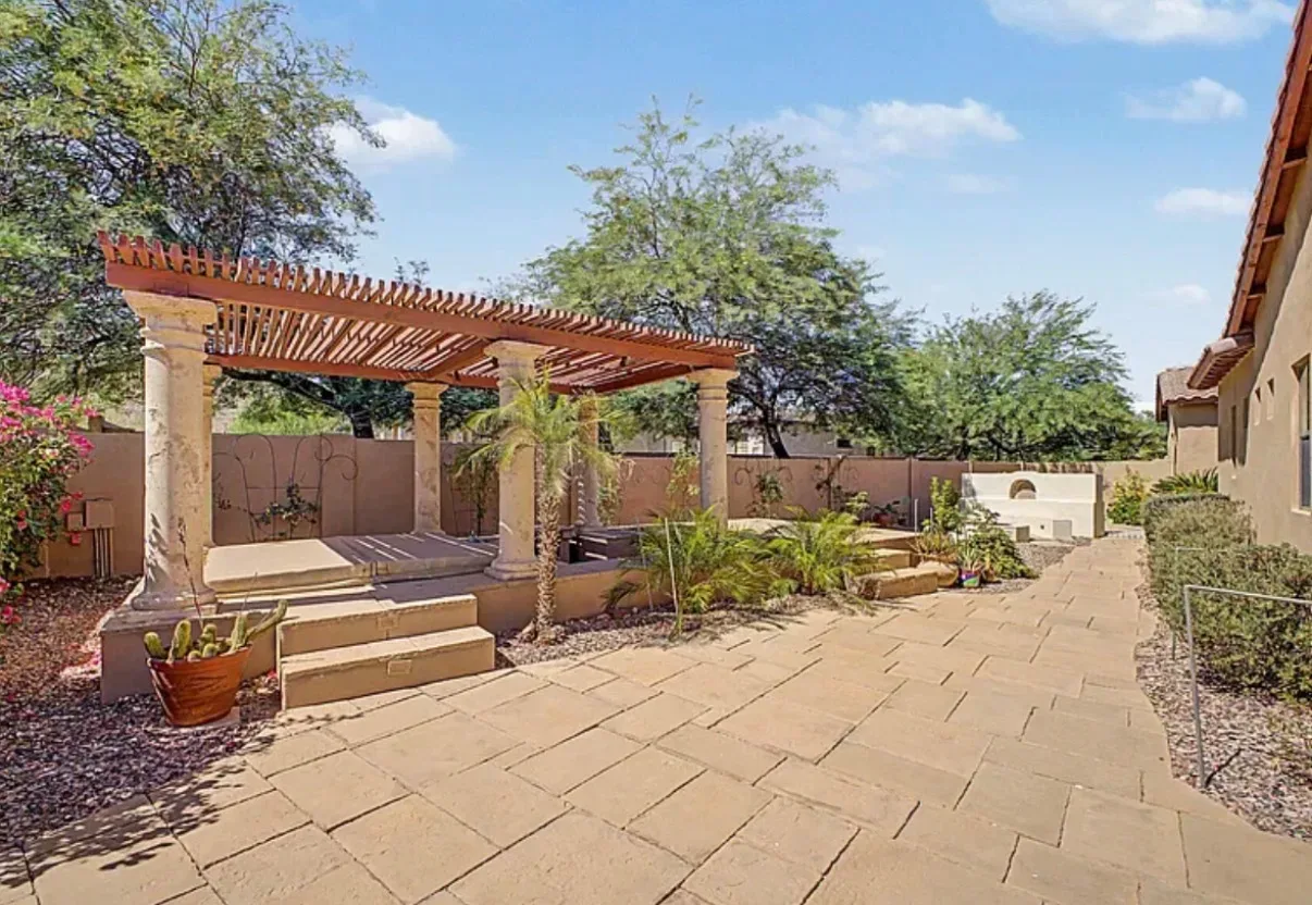 Paved backyard patio with a pergola and potted cactus