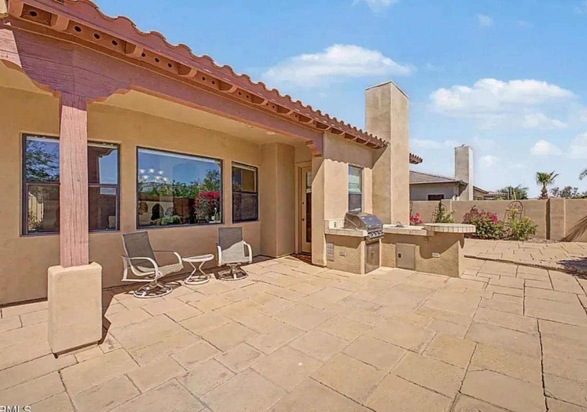 Backyard patio with a built-in outdoor kitchen and grill under a covered structure