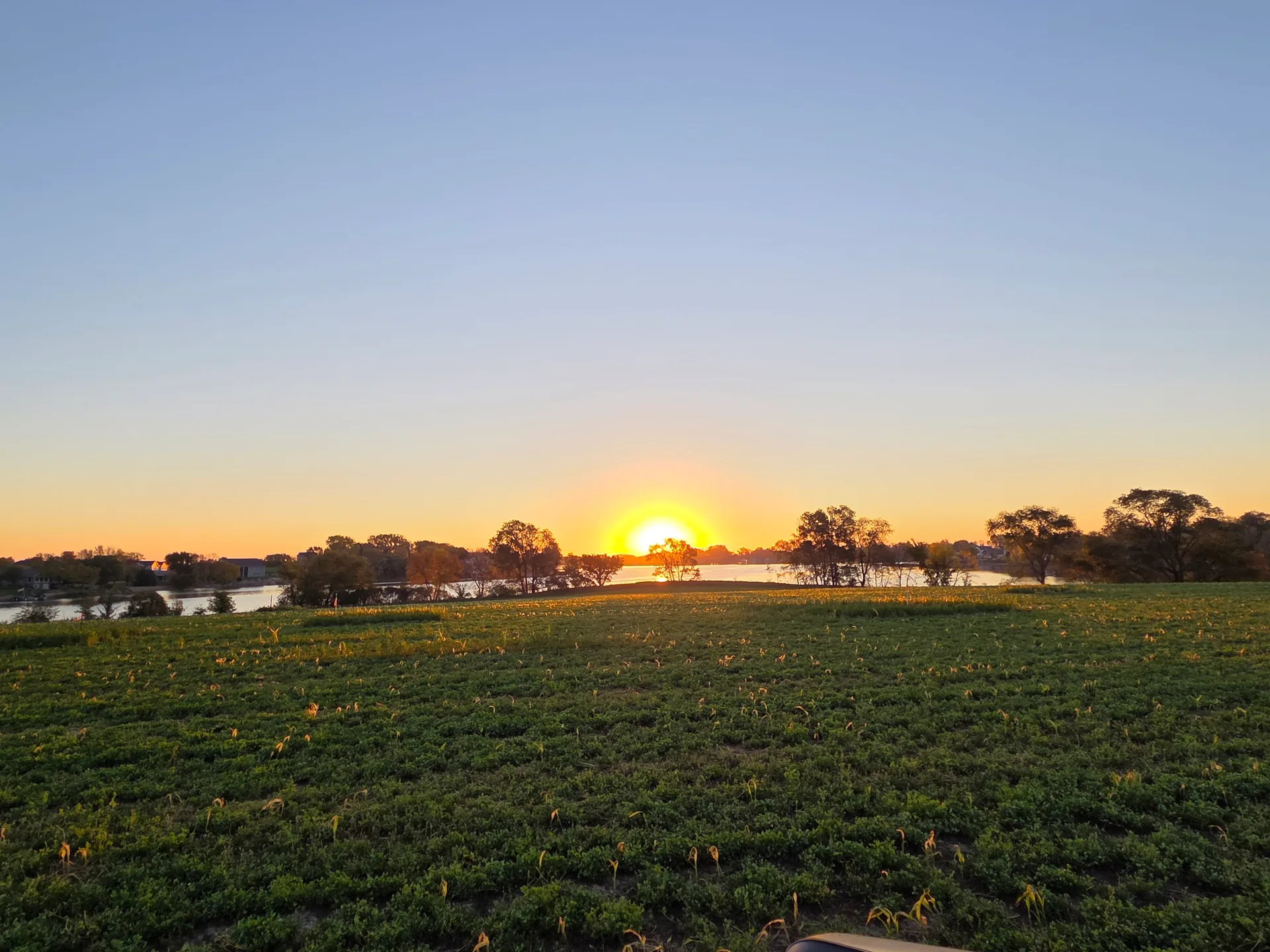 Sunset over the vacant lakefront lot on Swan Lake, open field leading to the shoreline