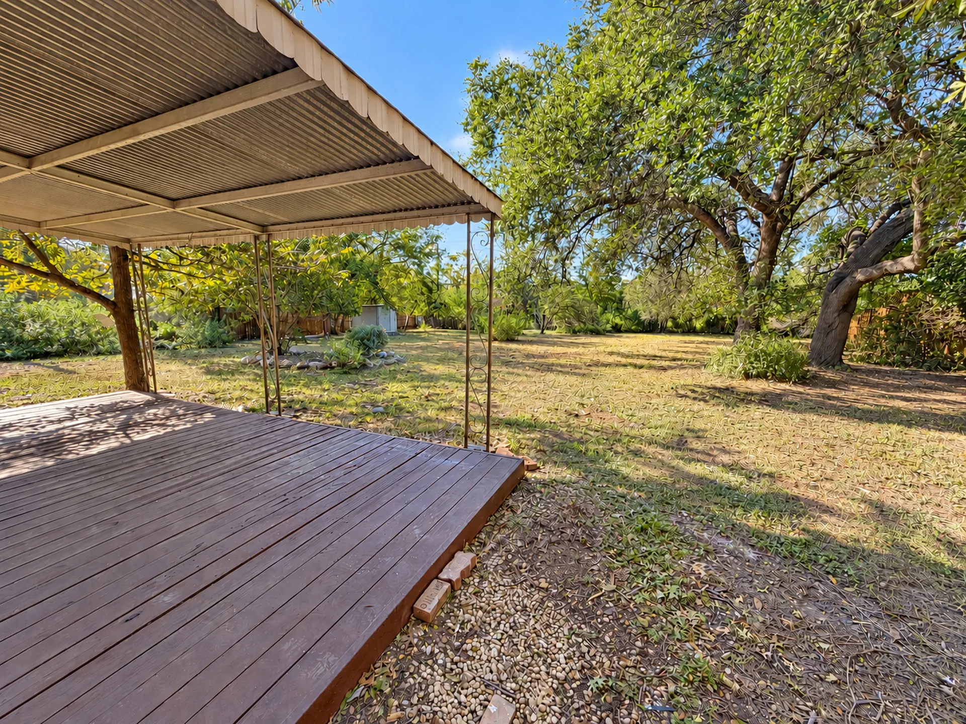 Covered wood deck in the backyard beneath mature oak trees