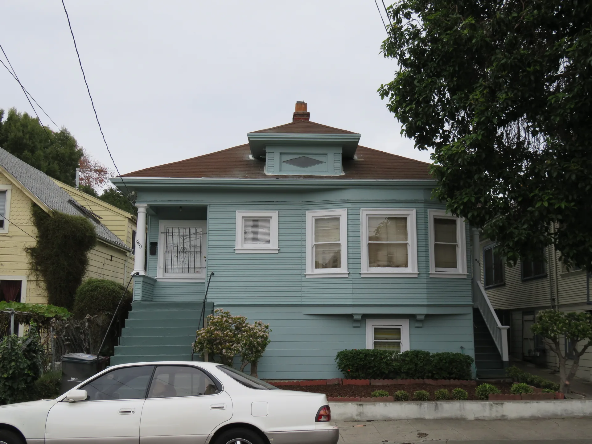 Front exterior facade of the sold duplex at 840–842 E 20th Street, Oakland, CA 94606, a vintage two-story building with light blue siding, a bay window, and a gabled roofline with a central dormer.