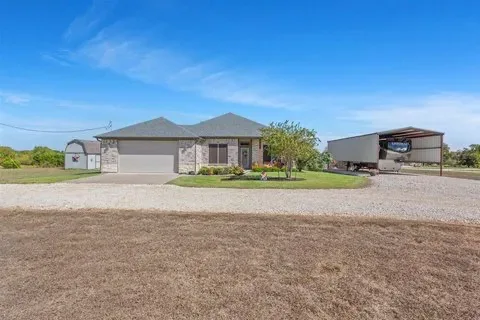 Exterior of a single-story home with a light stone and siding facade, a current listing at 6565 Mother Neff Pkwy in McGregor, Texas