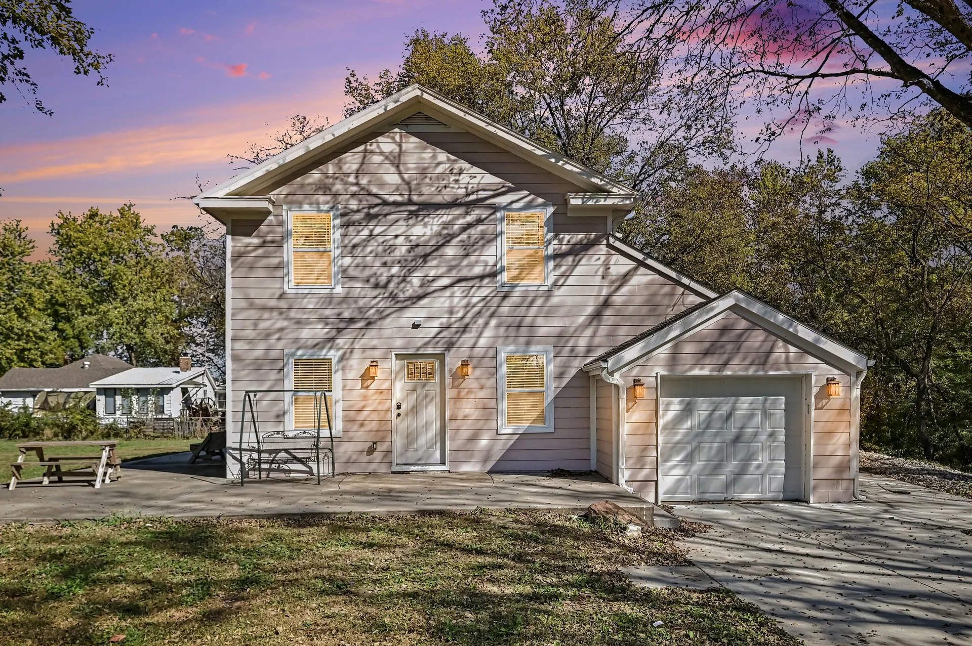 Front exterior of 190 W 4th Street in Holt, a two-story Craftsman home with light siding at twilight with warm lights on