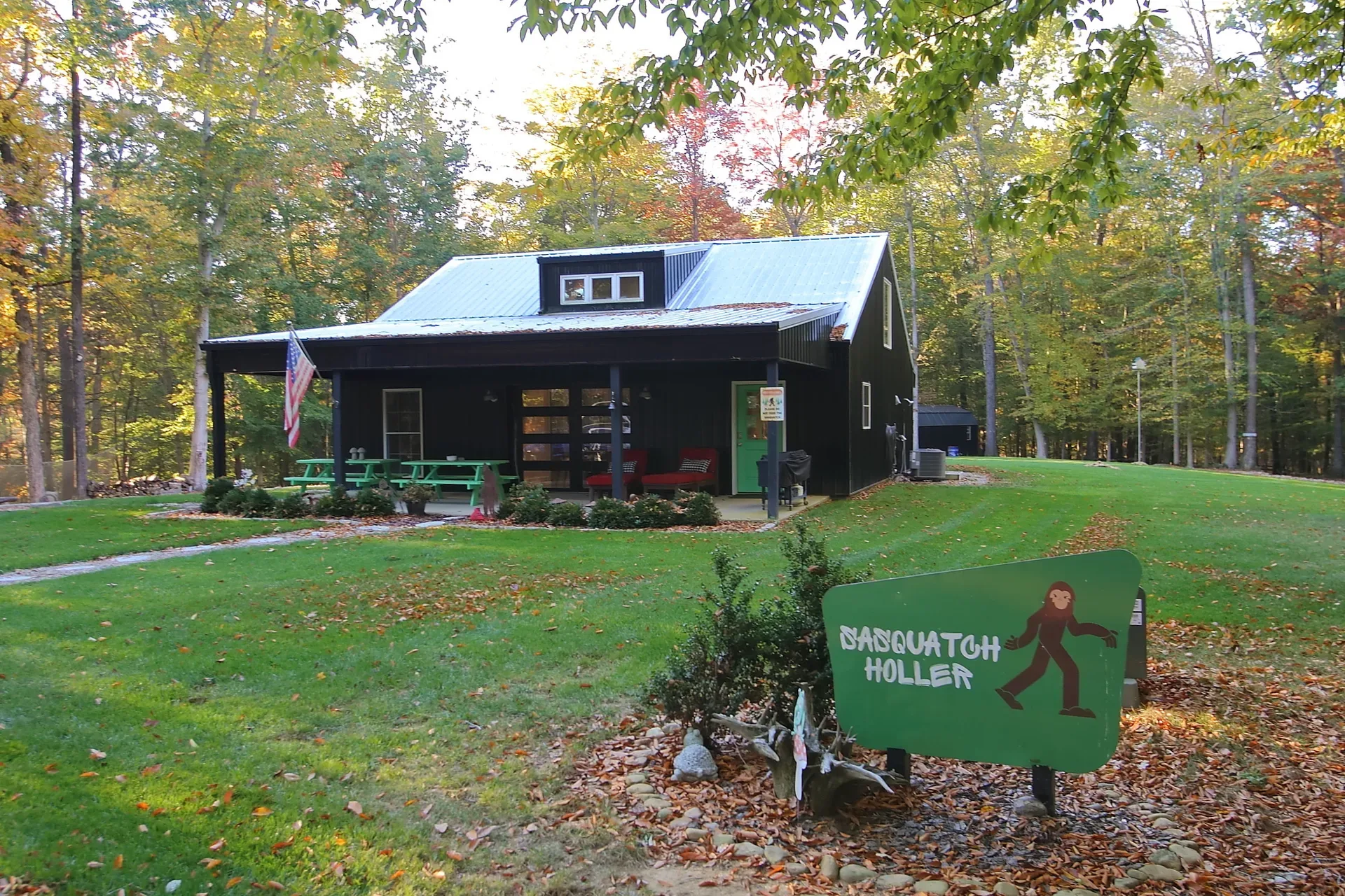 Barndominium in a wooded clearing at golden hour, autumn light through the trees