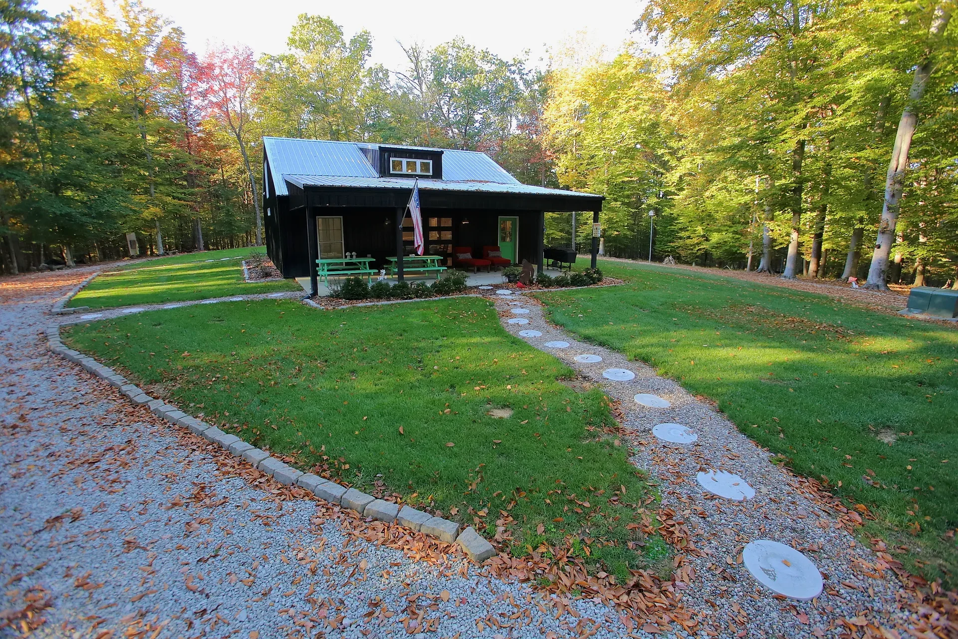 Front facade of the black-siding barndominium with covered porch and stone paver walkway