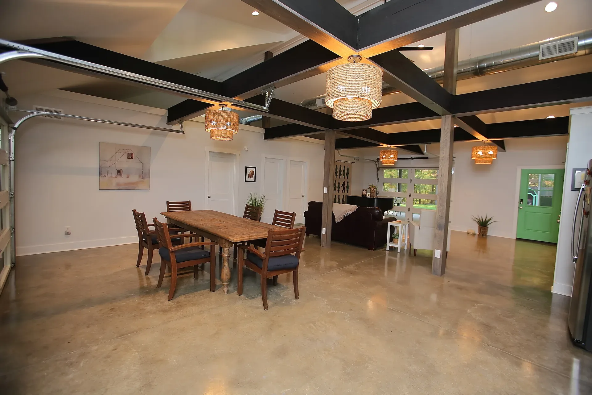 Open living and dining area with exposed beams and pendant lights