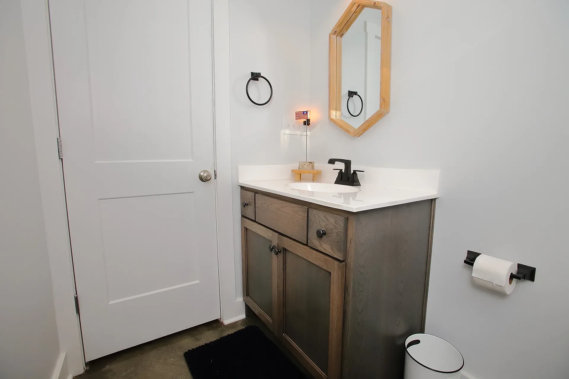 Bathroom vanity with dark wood cabinet and hexagon wood-framed mirror
