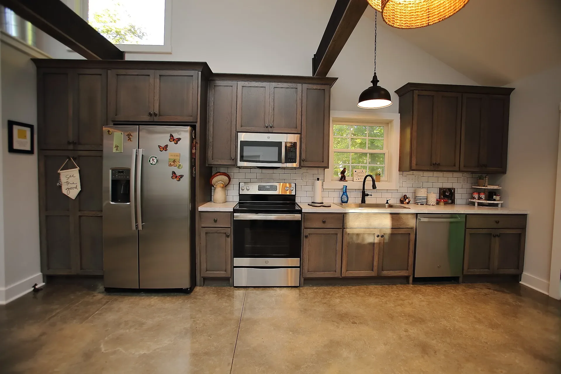 Kitchen with dark wood cabinetry, white subway tile backsplash and stainless appliances