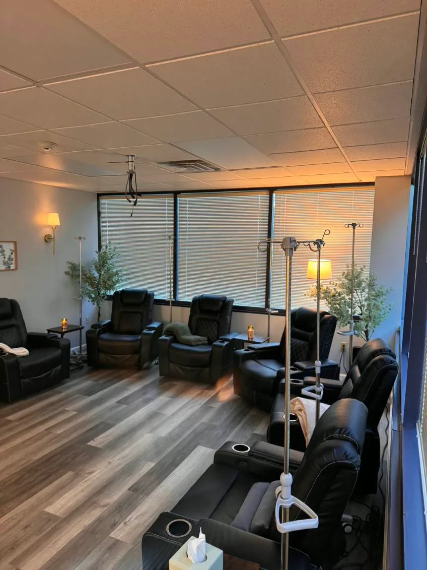 Quiet clinical infusion lounge with black leather reclining chairs and portable IV poles