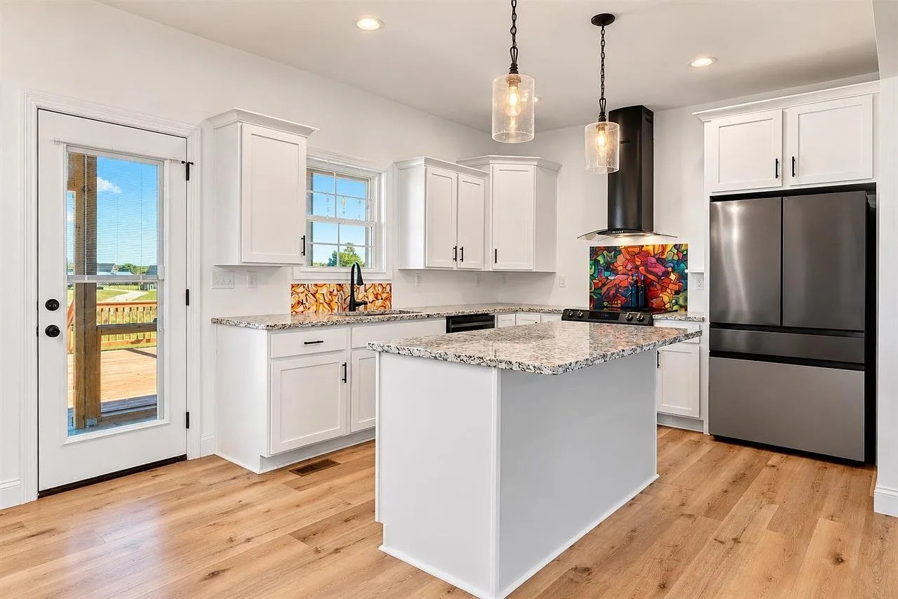 Kitchen with white cabinetry, granite countertops, and stainless steel appliances