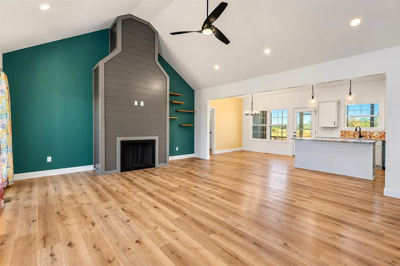 Vaulted-ceiling great room with hardwood floors opening into the kitchen