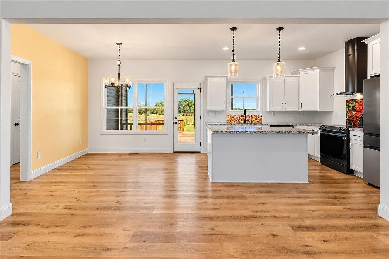 Open-concept kitchen and dining area with white cabinetry and granite countertops